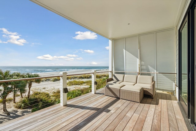 balcony with an outdoor hangout area, a water view, and a view of the beach