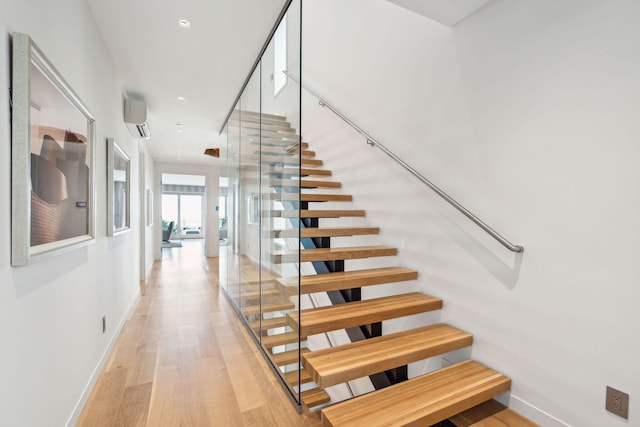 stairway featuring hardwood / wood-style floors and a wall unit AC