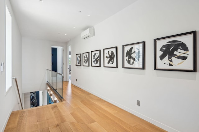 corridor with wood-type flooring and a wall mounted air conditioner