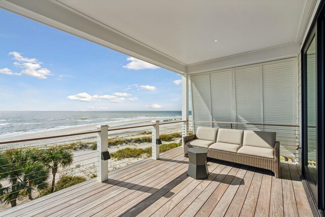 wooden terrace featuring a view of the beach, outdoor lounge area, and a water view