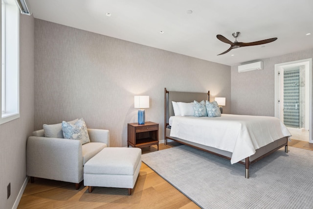 bedroom featuring light hardwood / wood-style flooring, ceiling fan, and a wall mounted air conditioner