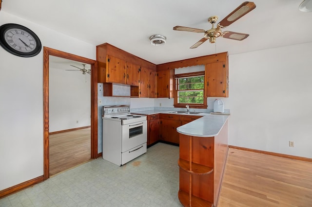 2708 Mawood Ave, North Charleston, SC 29406 - kitchen with white range with electric stovetop, ceiling fan, a peninsula, brown cabinetry, and baseboards