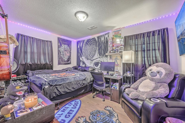 bedroom featuring a textured ceiling, light wood-type flooring, and visible vents