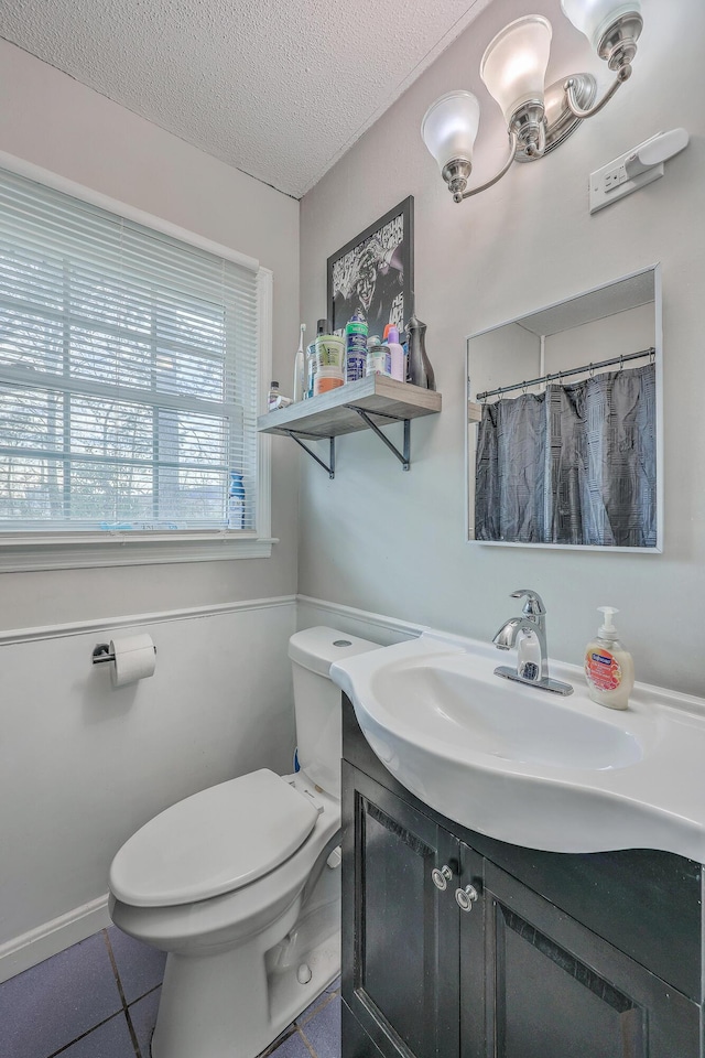 full bathroom featuring tile patterned flooring, vanity, toilet, and a textured ceiling