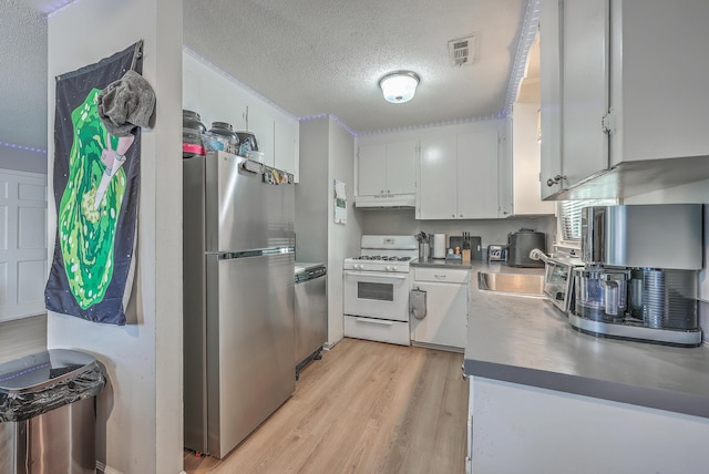 kitchen with a textured ceiling, light wood-style flooring, under cabinet range hood, stainless steel appliances, and white cabinets