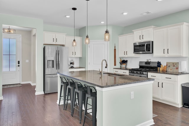 kitchen with a kitchen island with sink, sink, white cabinets, and appliances with stainless steel finishes