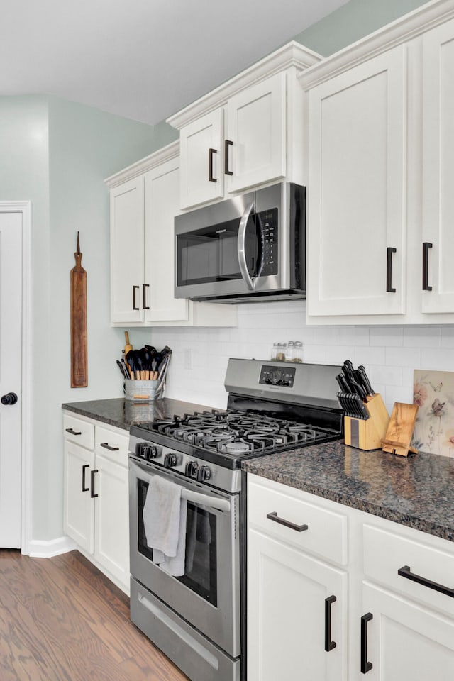 kitchen featuring backsplash, white cabinets, stainless steel appliances, and hardwood / wood-style flooring