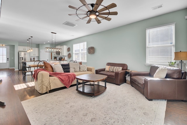 living room with ceiling fan with notable chandelier and wood-type flooring