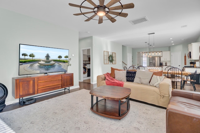 living room with a fireplace, washer / clothes dryer, ceiling fan, and light hardwood / wood-style floors