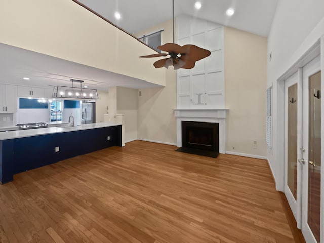 932 Portabella Ln, Charleston, SC 29412 - unfurnished living room with high vaulted ceiling, light wood-style floors, ceiling fan, a fireplace, and baseboards