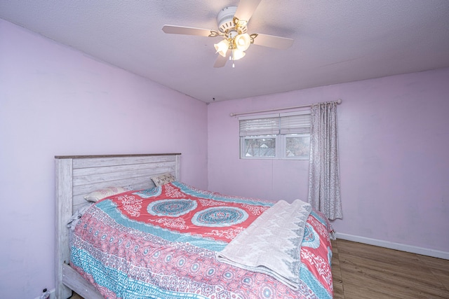 bedroom with ceiling fan, wood-type flooring, and a textured ceiling