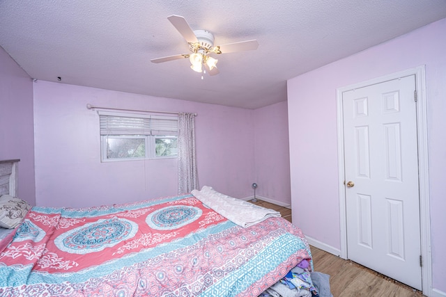 bedroom with ceiling fan, light hardwood / wood-style floors, and a textured ceiling