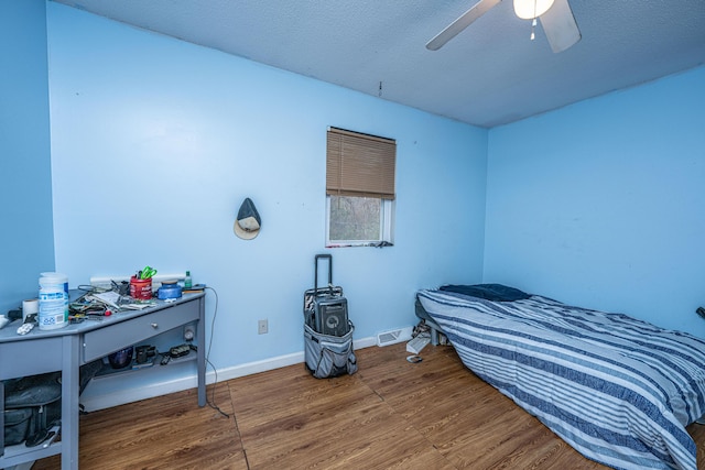 bedroom with ceiling fan, a textured ceiling, and dark wood-type flooring