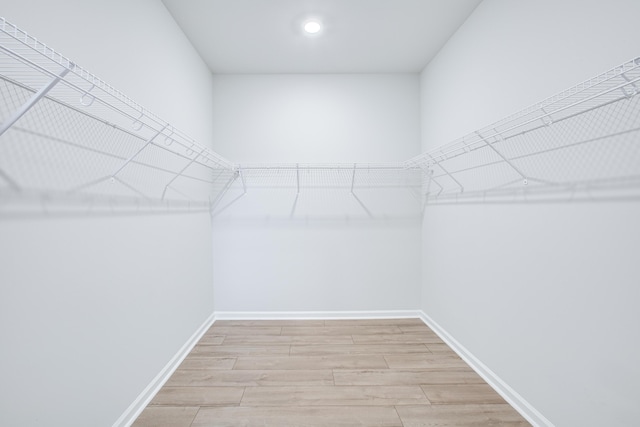 walk in closet with light hardwood / wood-style flooring