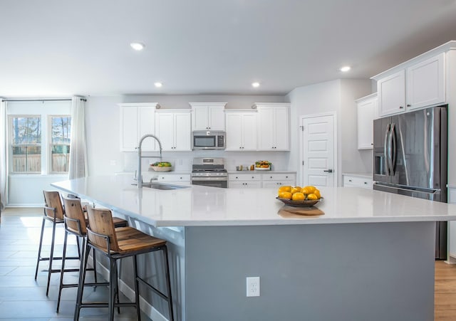 kitchen with white cabinetry, a large island, sink, and stainless steel appliances