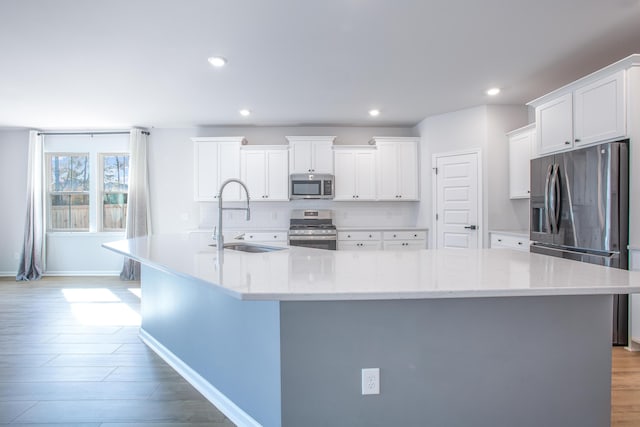 kitchen featuring appliances with stainless steel finishes, white cabinetry, a spacious island, and sink