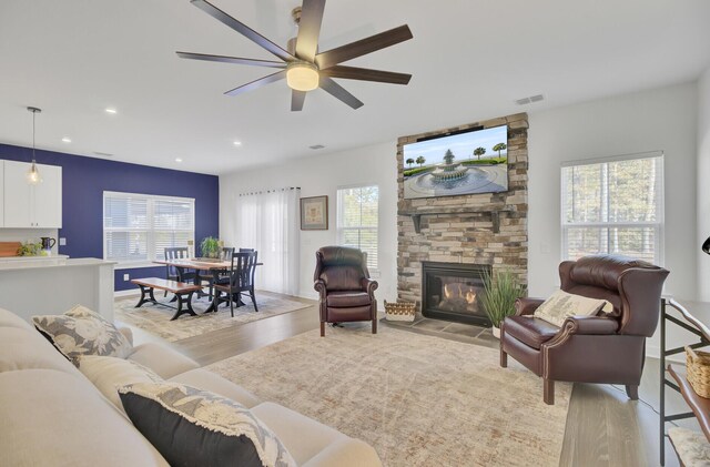 kitchen featuring light stone counters, white cabinets, sink, dishwasher, and a fireplace