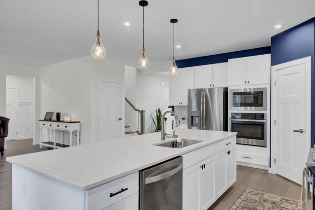 kitchen featuring a center island with sink, appliances with stainless steel finishes, and decorative light fixtures