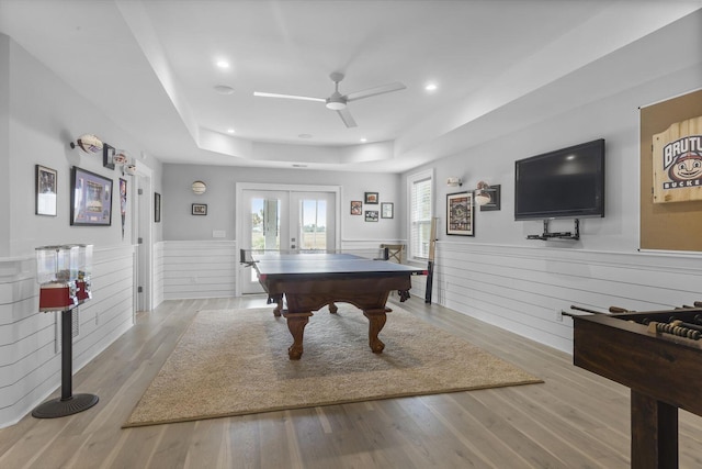 playroom featuring a tray ceiling, french doors, wainscoting, and wood finished floors