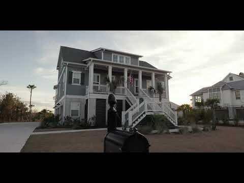 beach home featuring concrete driveway, a porch, and stairway