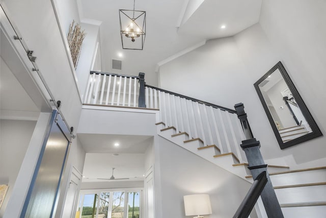 staircase with recessed lighting, visible vents, a towering ceiling, and a barn door