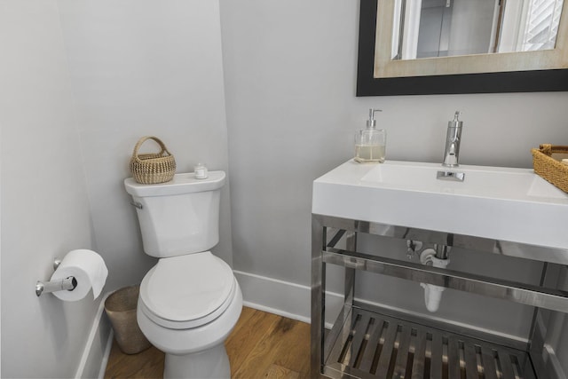 bathroom with toilet, baseboards, and wood finished floors