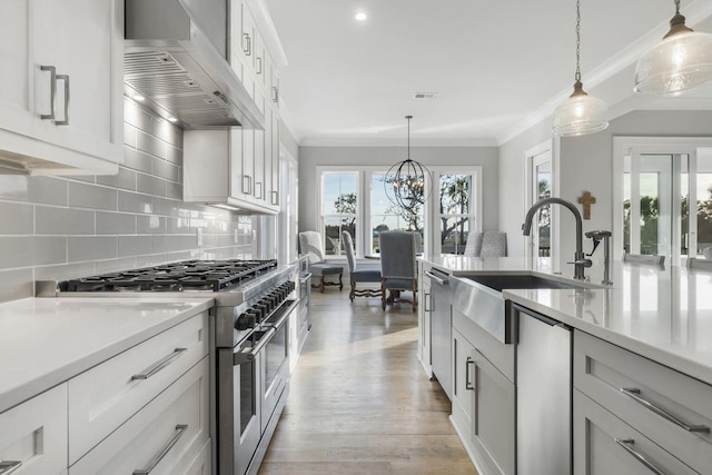 kitchen with wall chimney range hood, plenty of natural light, appliances with stainless steel finishes, and a sink