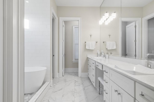 bathroom featuring double vanity, marble finish floor, a sink, and a soaking tub