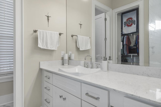 bathroom with a walk in closet and vanity