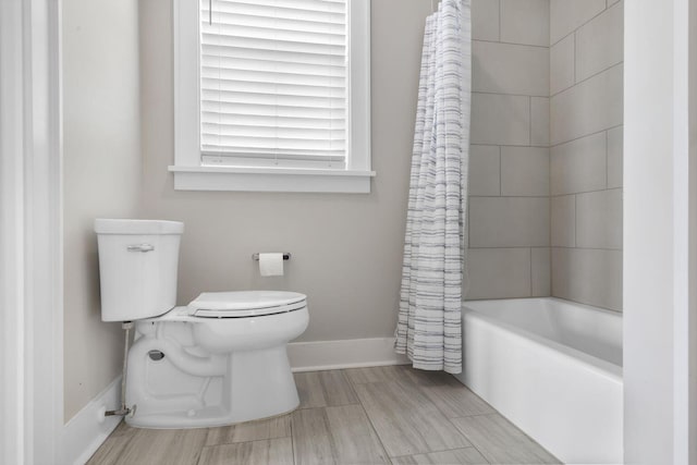 full bathroom featuring toilet, wood tiled floor, baseboards, and shower / bath combo with shower curtain