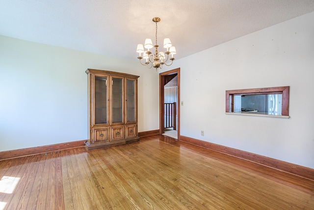 interior space featuring baseboards, light wood finished floors, and a chandelier