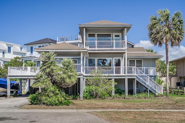 view of front of property with roof with shingles, a porch, stairway, and a balcony