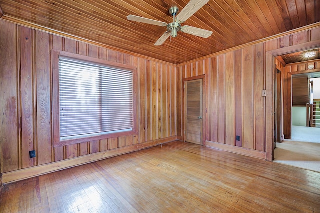 unfurnished room with wood walls, a ceiling fan, hardwood / wood-style flooring, and wooden ceiling
