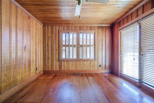 empty room featuring wood ceiling, visible vents, wood walls, baseboards, and wood-type flooring