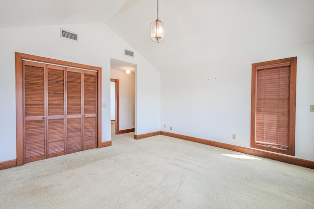 unfurnished bedroom featuring baseboards, vaulted ceiling, light colored carpet, and visible vents