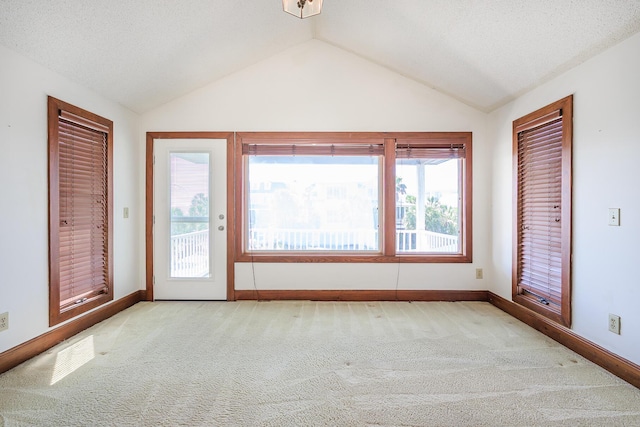 spare room with carpet floors, baseboards, and vaulted ceiling