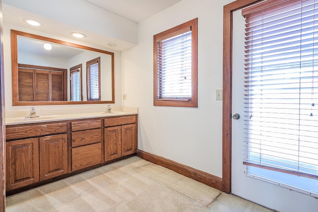 bathroom with baseboards, a sink, and a wealth of natural light