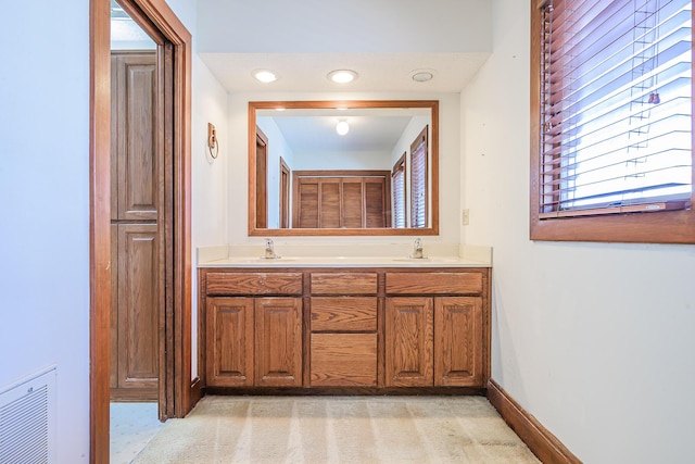 full bath with baseboards, a sink, double vanity, and visible vents