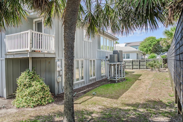 view of side of property featuring board and batten siding, fence, and a balcony