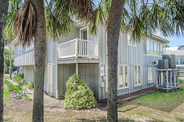 view of home's exterior with board and batten siding, cooling unit, and a balcony