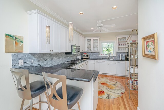 5847 Back Bay Dr, Isle Of Palms, SC 29451 - kitchen with stainless steel appliances, light wood-type flooring, glass insert cabinets, crown molding, and white cabinets