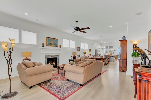 living room with a fireplace, light hardwood / wood-style floors, and ceiling fan