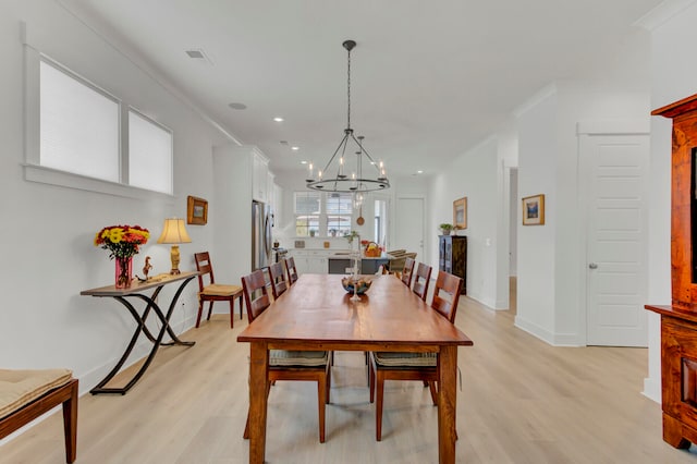 dining room featuring light hardwood / wood-style flooring, a chandelier, and ornamental molding