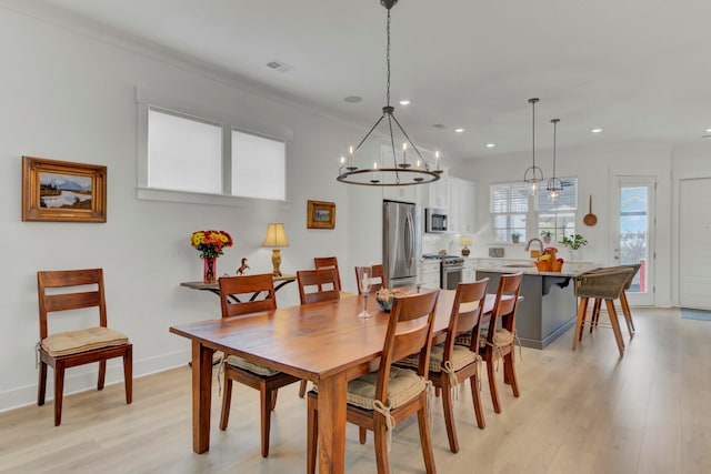 dining space with a chandelier, light hardwood / wood-style floors, and sink