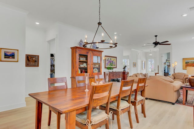 dining area with ceiling fan with notable chandelier, crown molding, and light hardwood / wood-style flooring