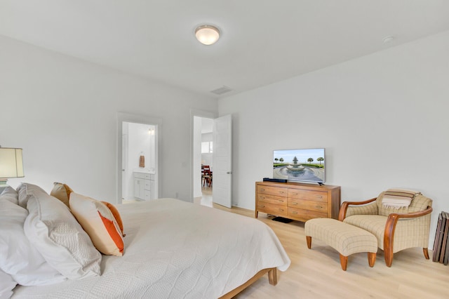 bedroom with hardwood / wood-style floors and ensuite bath