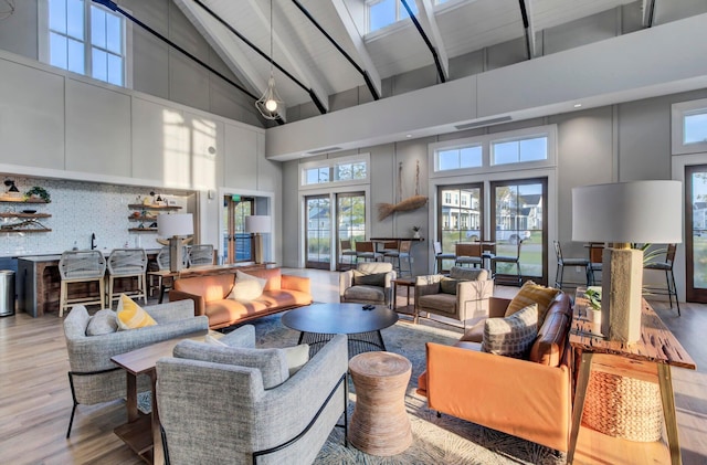 living room featuring beam ceiling, french doors, high vaulted ceiling, and light hardwood / wood-style flooring