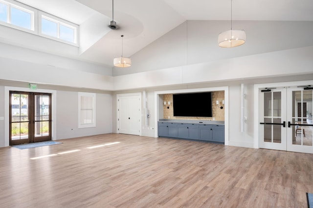 unfurnished living room featuring ceiling fan, light hardwood / wood-style floors, high vaulted ceiling, and french doors