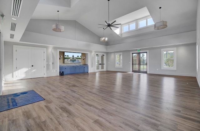 unfurnished living room featuring hardwood / wood-style floors, ceiling fan, and high vaulted ceiling