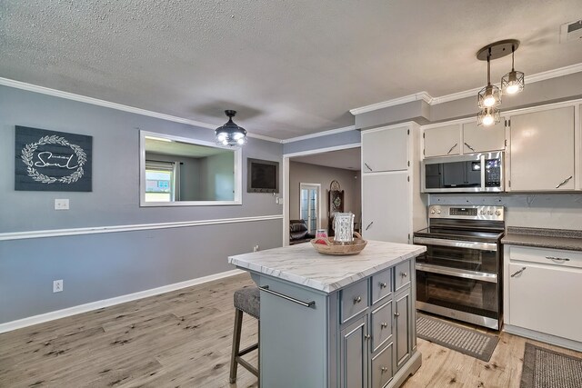 kitchen with stainless steel appliances, light hardwood / wood-style floors, crown molding, gray cabinets, and pendant lighting